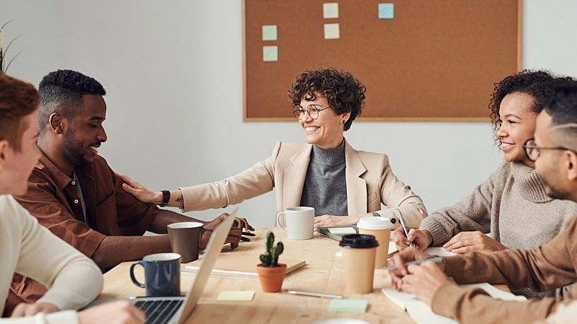 Five employees gather at a conference table in an office.