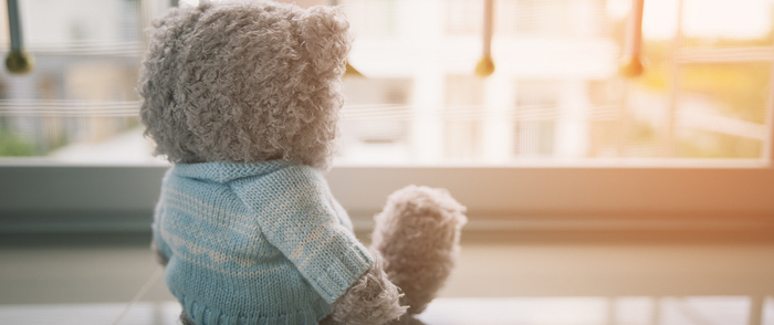 A teddy bear sits alone in a room as the sun rises.