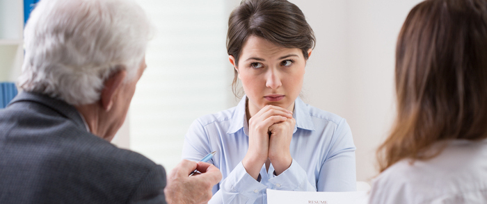 Focus on the Candidate Experience and Boost Your Bottom Line Women being interviewed by two people appears tense.