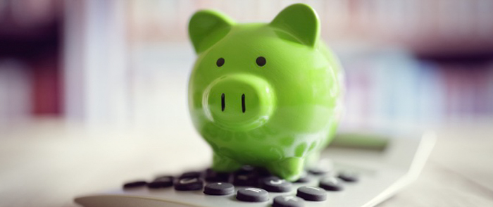 A green piggy bank sits on a calculator.