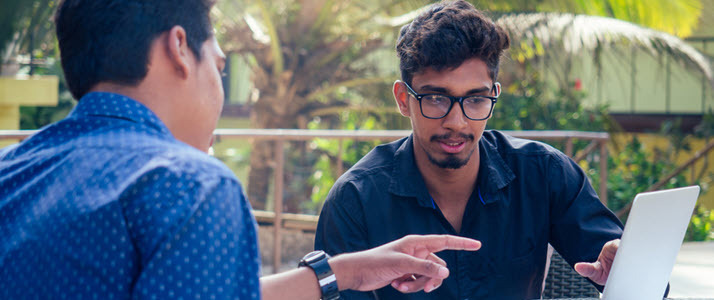 International Business Is Poised to Grow Two Indian businessmen chatting looking at laptop