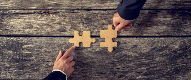 Merger and Acquisitions Two fitting puzzle pieces are put together.