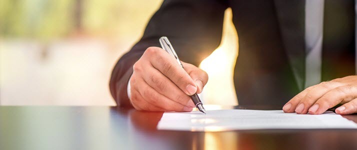 man signing piece of paper on a desk