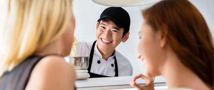 A smiling employee takes a customer's order.