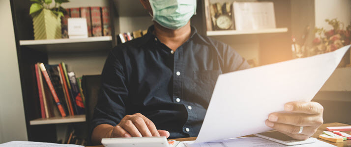 A businessman wears a mask in his office