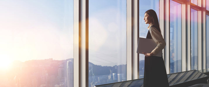 successful female professional looking out office window successful female professional looking out office window