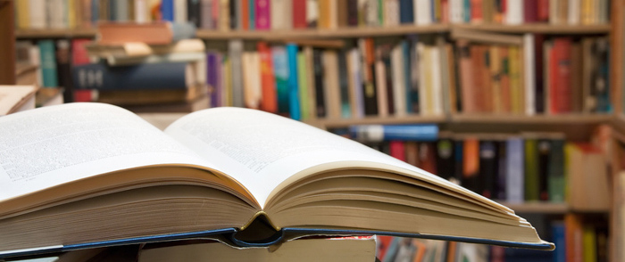 An open book sits on a desk in a library.