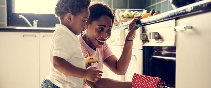 youngmother with child pulling cookies from oven