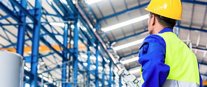 An industrial worker wearing a hard hat is in a factory.