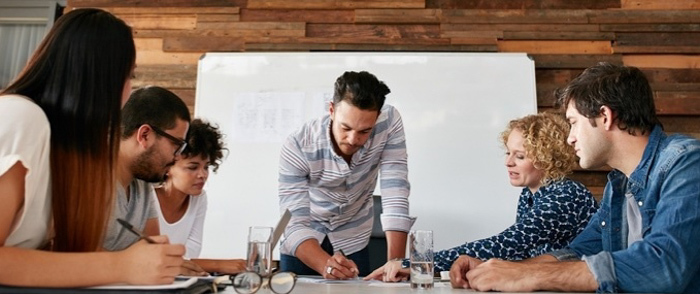 Two financial leaders discuss a topic. One is taking notes and the other is staring at the computer.