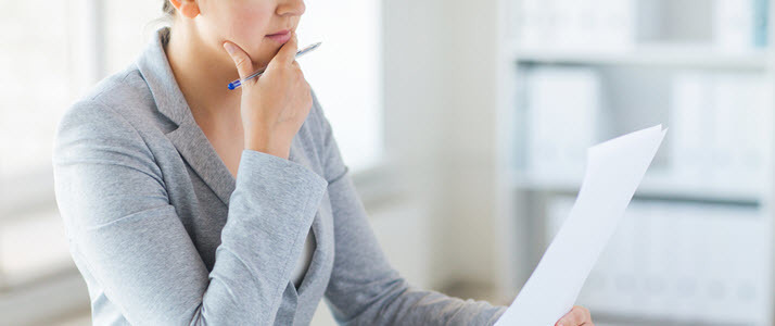 Woman at desk looks at piece of paper Woman at desk looks at piece of paper