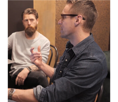 Cody Pellerin in an Americano Lounge office speaking during a meeting, with another man listening in the background.