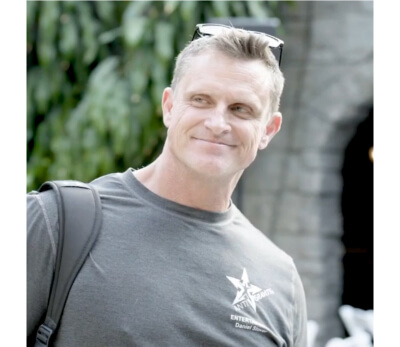 Daniel Stover standing outdoors with a slight smile, wearing a backpack and an Antigravity NTF t-shirt.