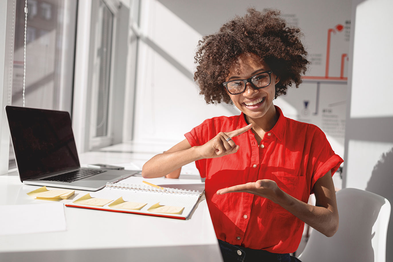 A smiling associate sitting at a desk using ASL.