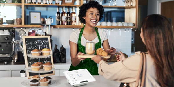 Clover countertop point of sale terminal in use at a café as a barista serves a customer.